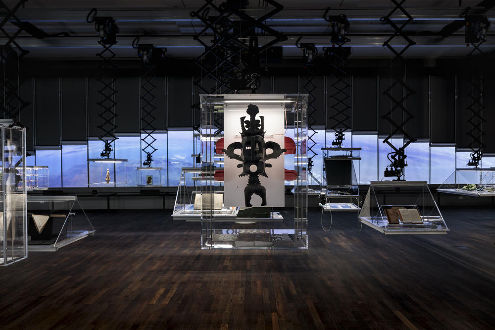 Blick in die Eröffnungsausstellung des Humboldt Labors. Im Vordergrund: Eine Maske des beninischen Künstlers Romuald Hazoumè, im Hintergrund die digitale Wand.