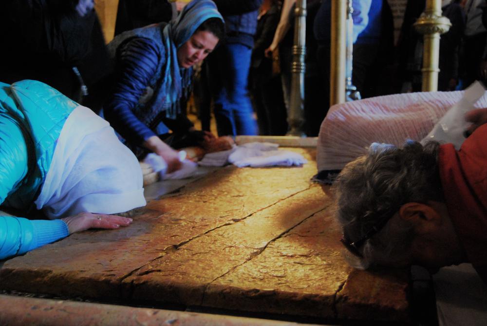 Visitors to the Church of the Holy Sepulchre pray at the Stone of Anointing in the entrance area. Some rub their souvenirs over the stone, others kiss it. Jesus is said to have been anointed on the stone after he was removed from the cross.