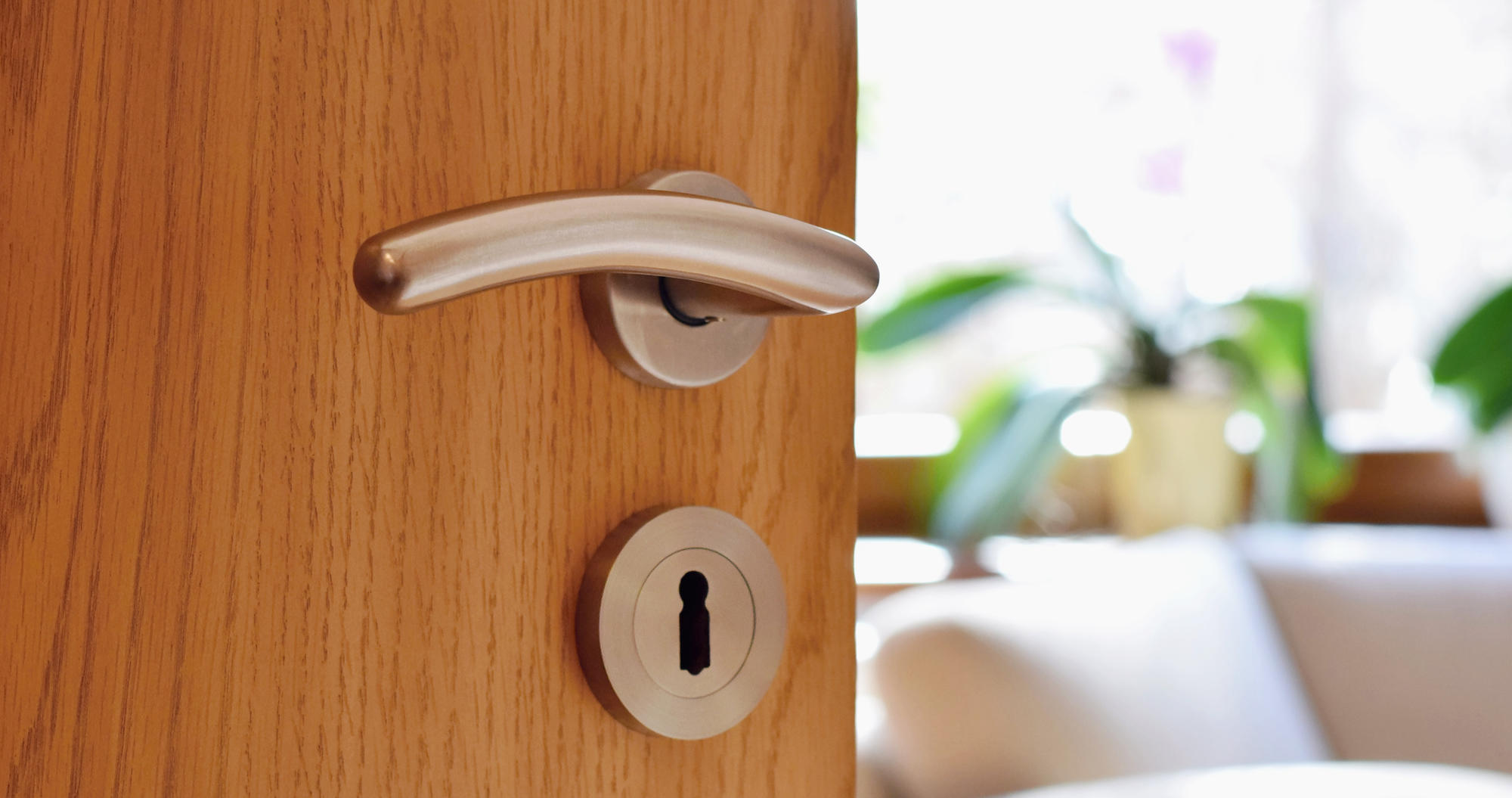 Symbolbild Beratung (geöffnete Tür zu einem hellen, freundlichen Raum mit Sitzgelegenheit)